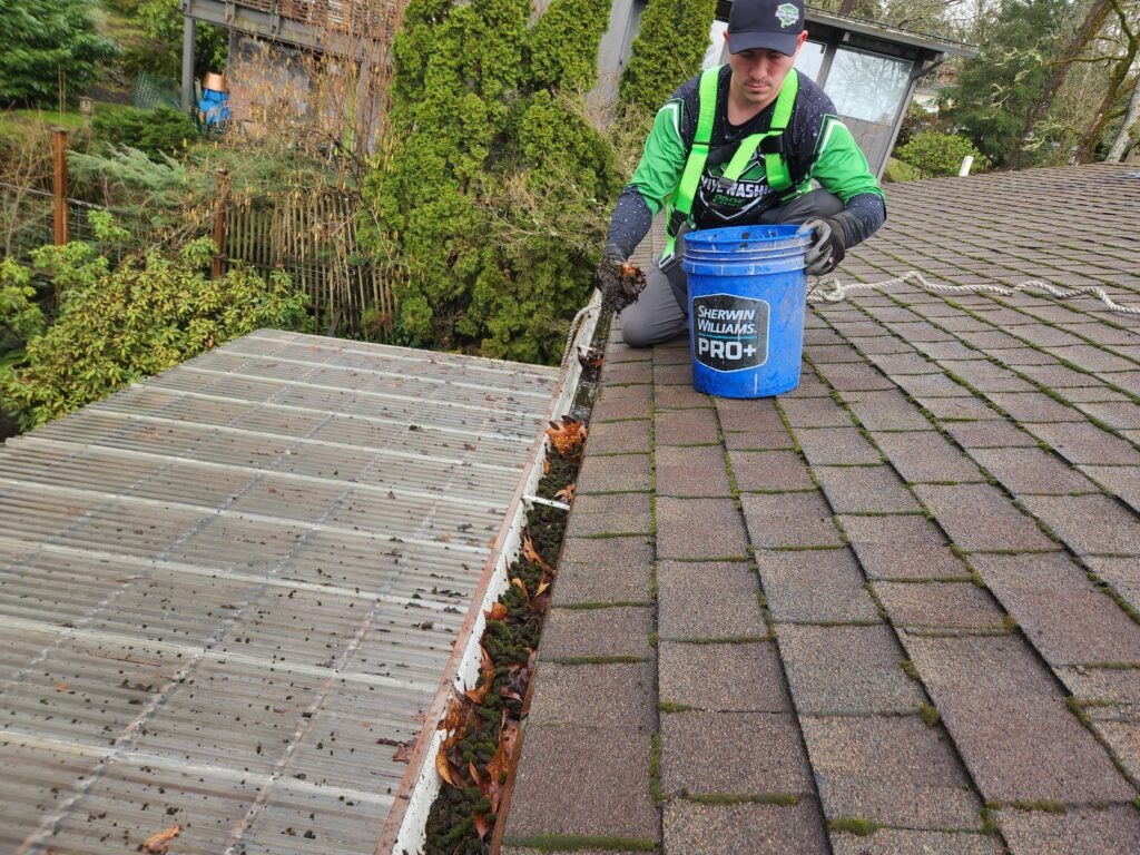 man cleaning gutters by hand in Eugene Oregon.